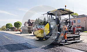 Worker operating asphalt paver machine during road construction and repairing works. A paver finisher, asphalt finisher