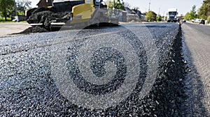 Worker operating asphalt paver machine during road construction and repairing works. A paver finisher, asphalt finisher