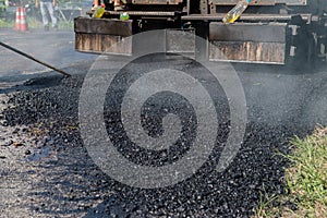 Worker operating asphalt paver machine during road construction