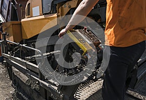 Worker operating asphalt paver machine during road construction and repairing works. A paver finisher, asphalt finisher