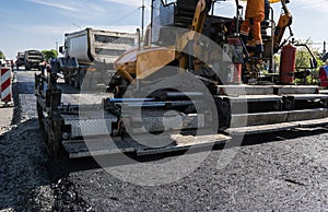 Worker operating asphalt paver machine during road construction and repairing works. A paver finisher, asphalt finisher