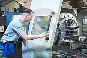 Worker operating a CNC lathe in factory