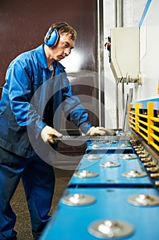 Worker operating guillotine shears machine photo