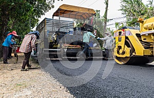 Worker operating industrial asphalt paver machine during highway construction