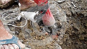 Worker operating a jackhammer to dig up a road for pipelining in Uttarakhand, India. Illustrating progress and development in