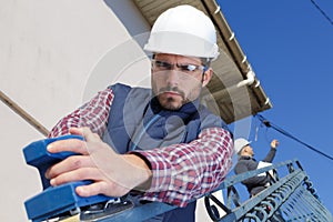 Worker operating sky lift to do maintenance work outdoor