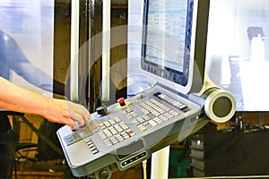 Worker, operator of the control panel of the program of operation of a high-precision CNC machining center, processing the manufac