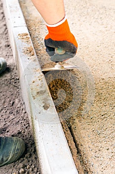 Worker with orange glove uses paving trowel