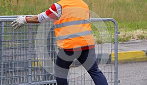 worker with orange high-visibility vest while moving the fences