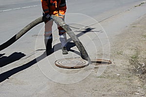 The worker ossenizator pumped sewage out of the sewage system through the hatch in the street. sewerage worker on street cleaning