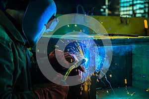 The worker in overalls and a protective mask welds metal with a welding machine. Profession welder. photo