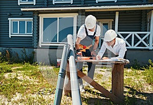 Worker in overalls putting spirit level on drawings