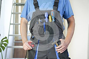 Worker in overalls with tools stands against the background of repair