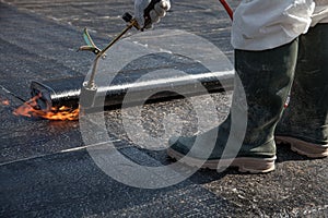A worker overlay the roofing material on the flat concrete surface