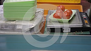 Worker packages tomatoes in plastic green trays her work place closeup.