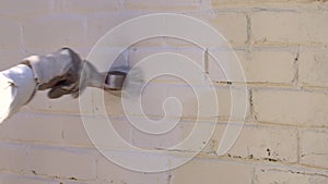 Worker with paintbrush painting brick house facade