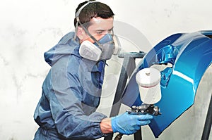 Worker painting blue bumper.
