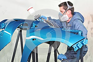 Worker painting blue bumper.