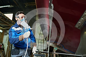 Worker painting boats in yacht workshop