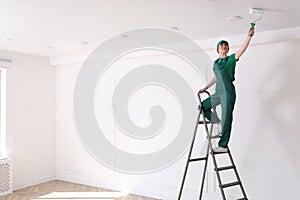 Worker painting ceiling with white dye indoors, space for text