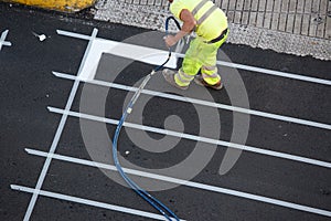 Worker painting a pedestrian crosswalk road