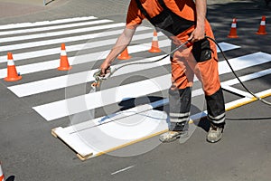 Worker is painting a pedestrian crosswalk. Technical road man worker painting and remarking pedestr