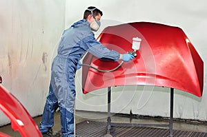 Worker painting a red bonnet.