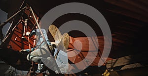 Worker painting on the side of ship at shipyard