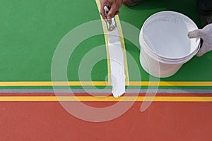 Worker painting the sideline on the floor for outdoor stadium