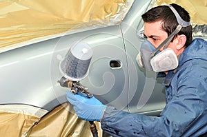 Worker painting silver car.