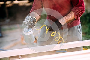 worker painting timber with spraygun, airgun. Carpentry details