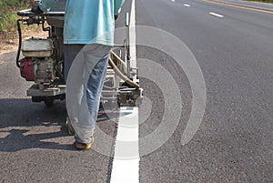 Worker painting traffic line with spraying eject machine. photo