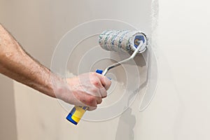 Worker painting wall in room. Painting walls with a roller.