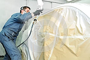 Worker painting white car side wall.