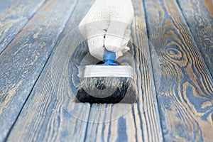 A worker painting a wooden wall. A man holding brush. A hand of worker painting wooden plank. A painter with paint brush