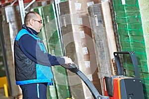 Worker with pallet truck stacking cardboxes