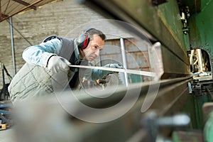 worker passing sheet metal through industrial machine photo