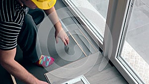 Worker with pencil make markings on laminate floor board