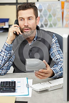 worker on phone holding sanitary drain pipes in workshop