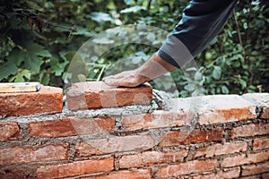 Worker placing and installing bricks on exterior wall on house construction