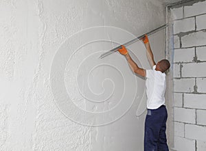 Worker plastering house walls, finishing walls. Wall screeding. Plastering walls techniques