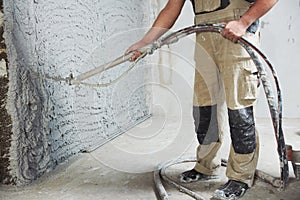 Plastering the interior wall with an automatic spraying plaster pump machine photo