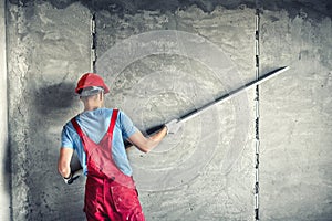 Worker with plastering tools renovating a house. builder worker plastering facade industrial building with leveler photo