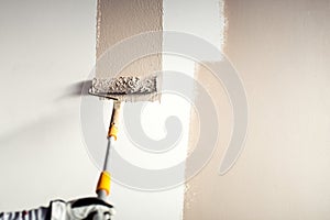 Worker plastering a wall, painting with paint brush decoration on interior walls