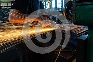 The worker polishes the metal with a grinding machine and sparks close-up.