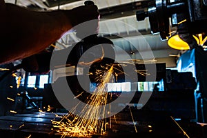 The worker polishes the metal with a grinding machine and sparks close-up.