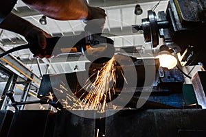 The worker polishes the metal with a grinding machine and sparks close-up.