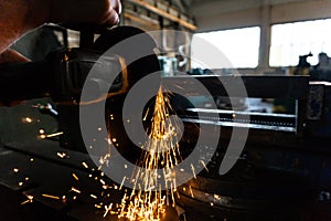 The worker polishes the metal with a grinding machine and sparks close-up.