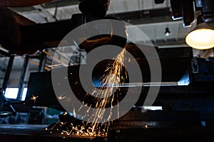 The worker polishes the metal with a grinding machine and sparks close-up.