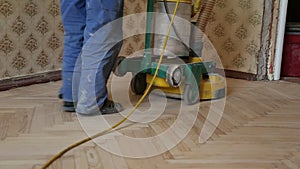Worker polishing old wooden parquet floor